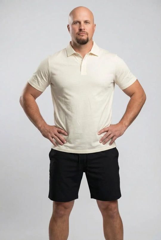 Man wearing a white polo shirt and black shorts on a gray background