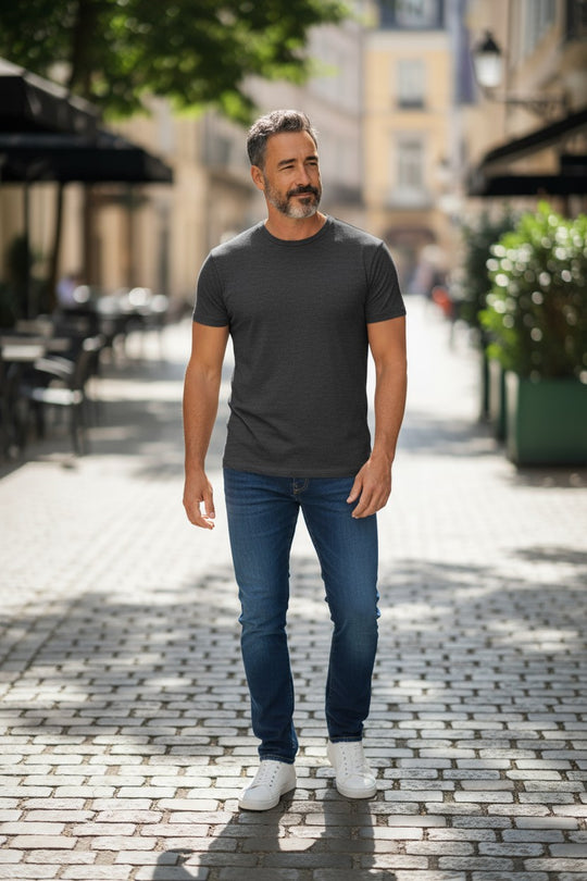 Man wearing a merino grey t-shirt and blue jeans standing on a street.