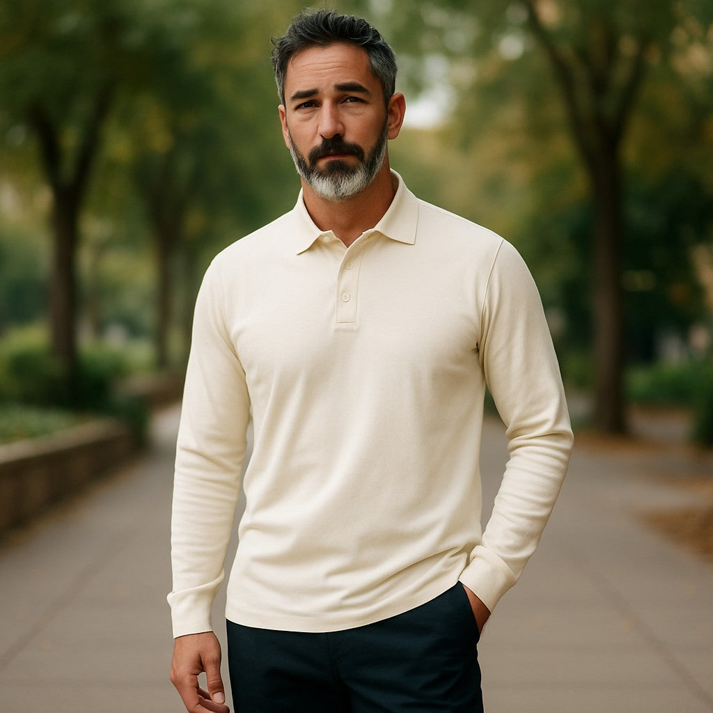 Man wearing a cream long-sleeve polo shirt standing outdoors with greenery in the background