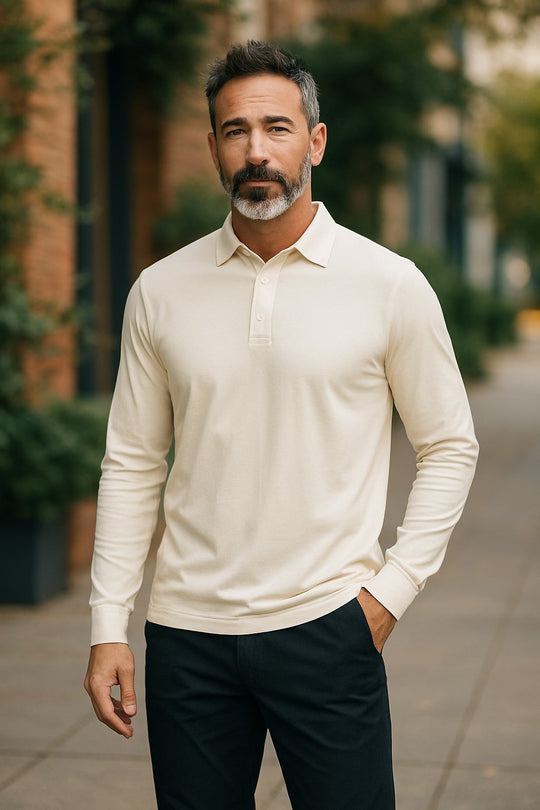 Man wearing a cream long-sleeve merino shirt and dark pants standing outdoors.