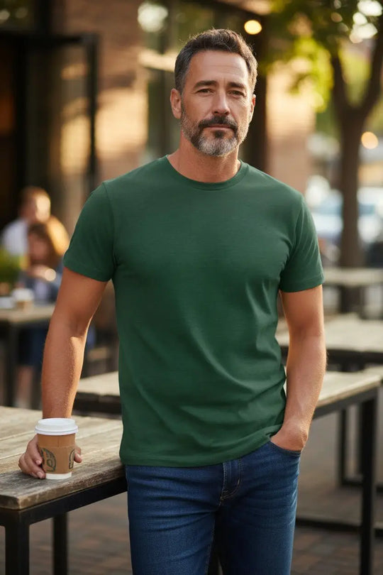 Man in a green t-shirt holding a coffee cup outdoors