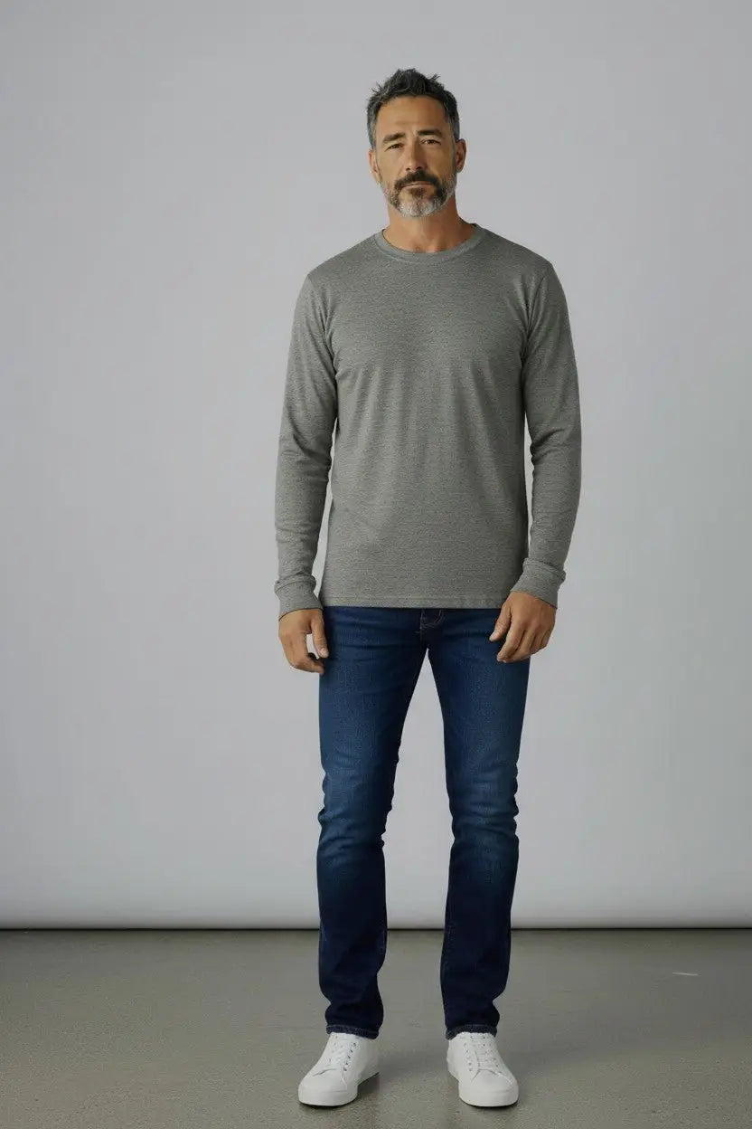 Man wearing a gray long-sleeve shirt and blue jeans against a plain background