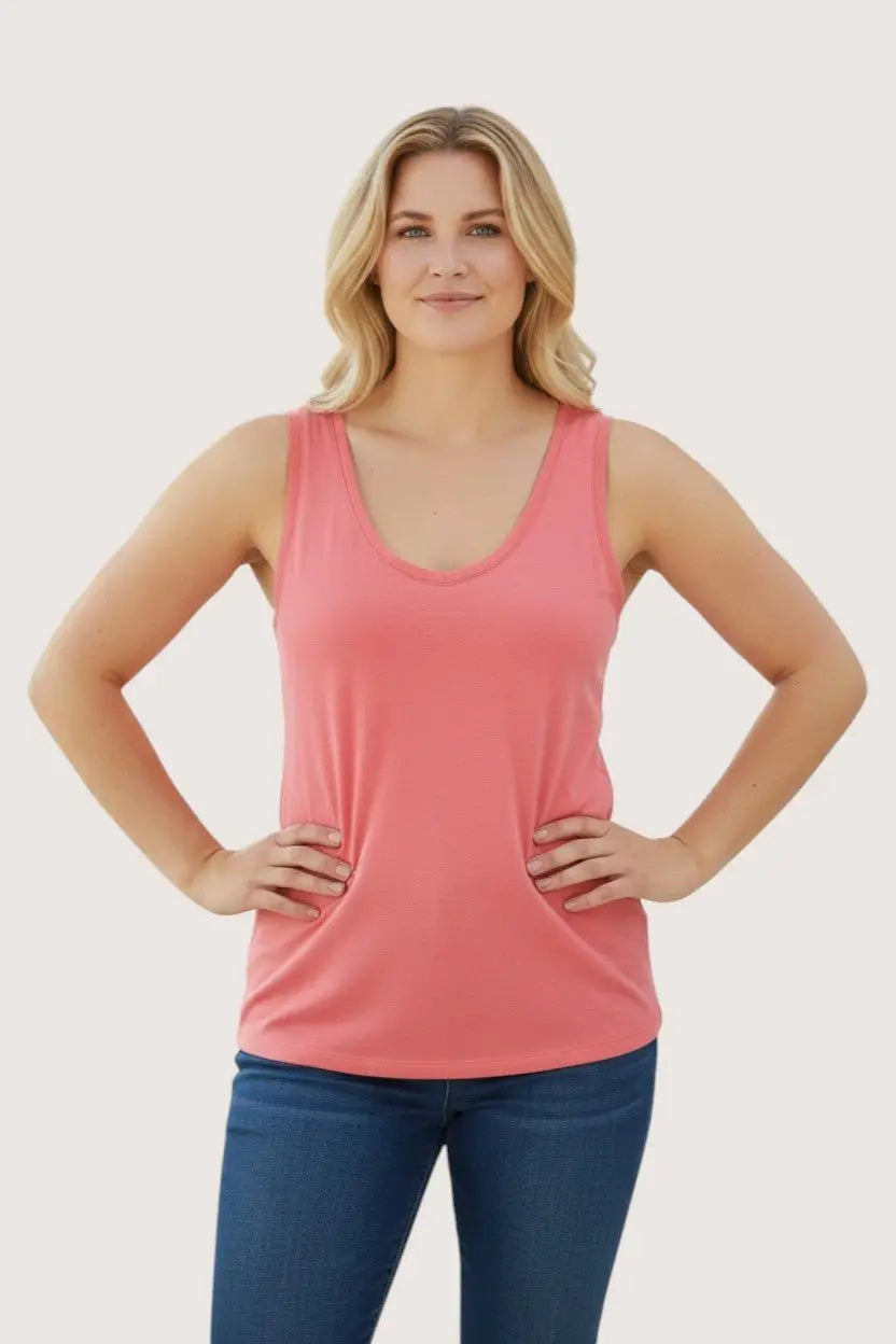 Woman wearing a pink tank top and blue jeans on a plain background