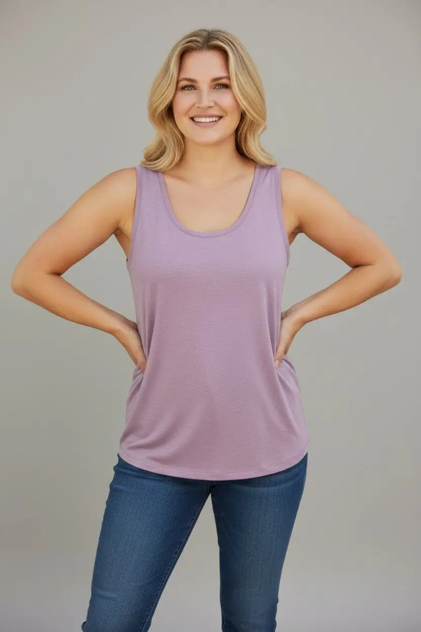 Woman wearing a purple tank top and blue jeans against a plain background