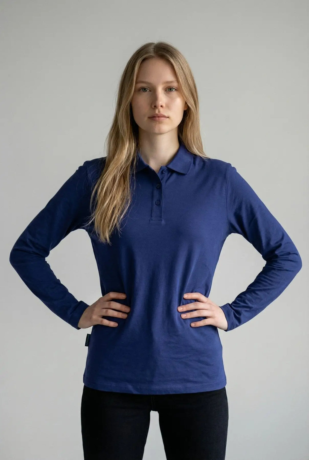 Woman wearing a blue long-sleeve polo shirt against a gray background