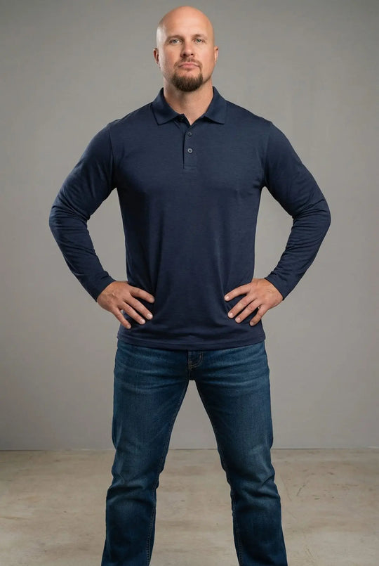 Man wearing a navy long-sleeve polo shirt and blue jeans against a gray background